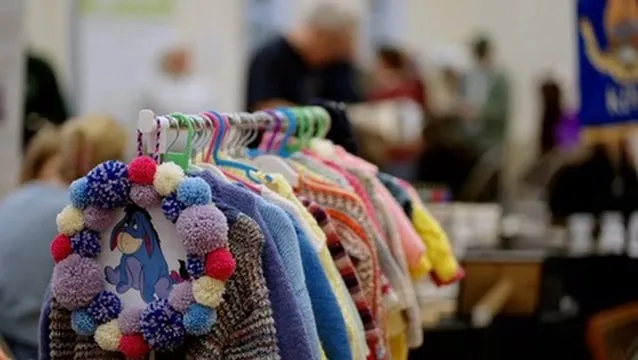 Colorful handmade woolen hats and accessories displayed at Aylesham Community Trust market for local community support and charity events.